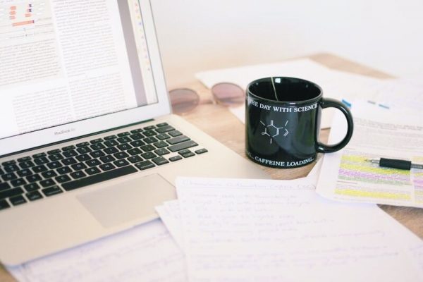 laptop with paper work and a mug of coffee