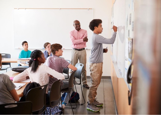 student in classroom writing on a white board